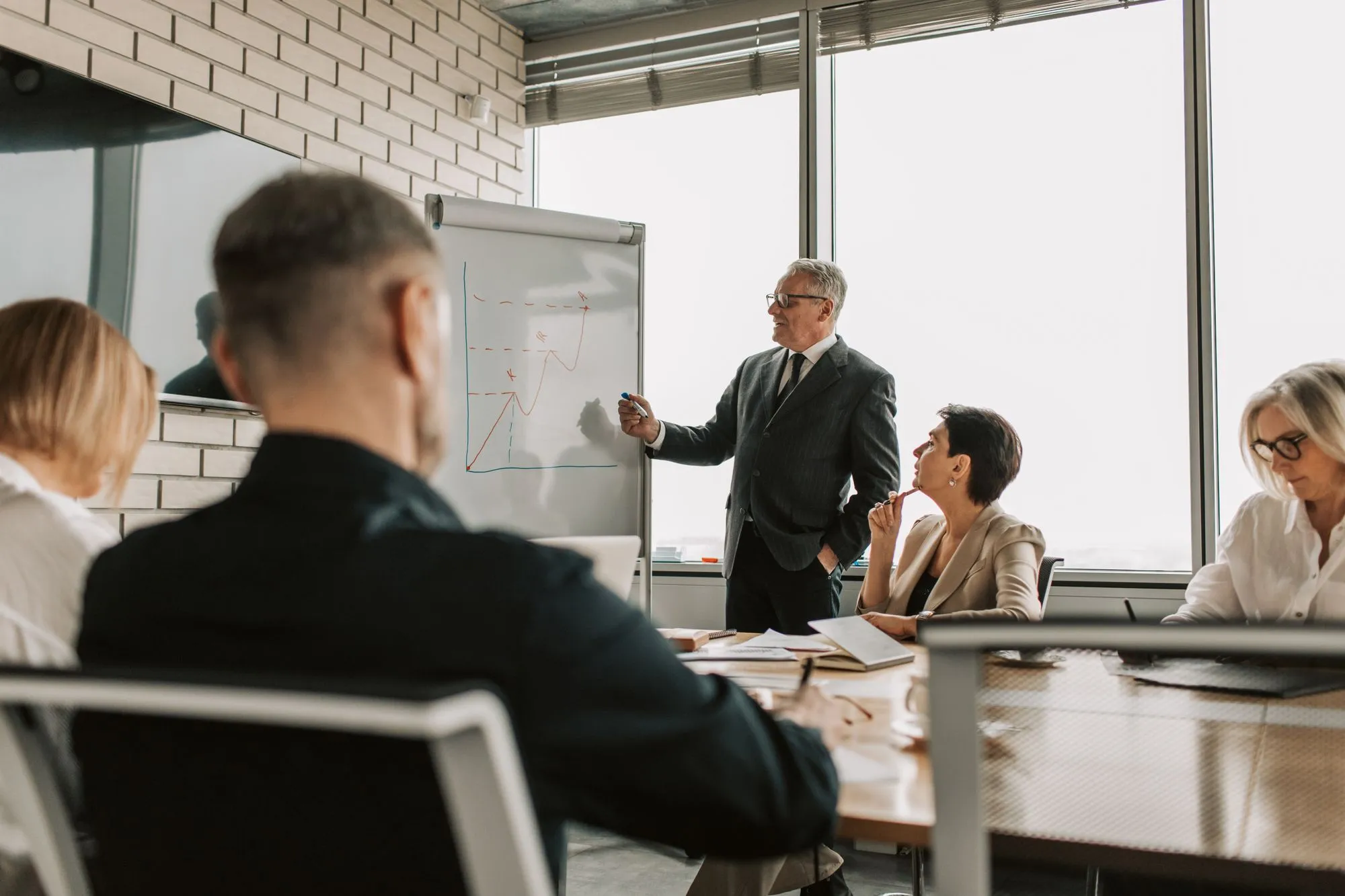 A senior leader presenting to colleagues in a meeting room.